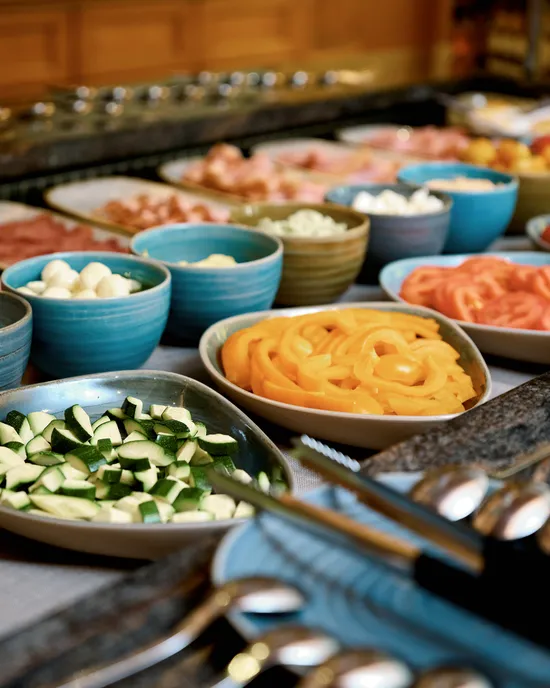 Farbenreiches Frühstücksbuffet mit frischem Gemüse, Käse und Aufschnitt in Keramikschalen